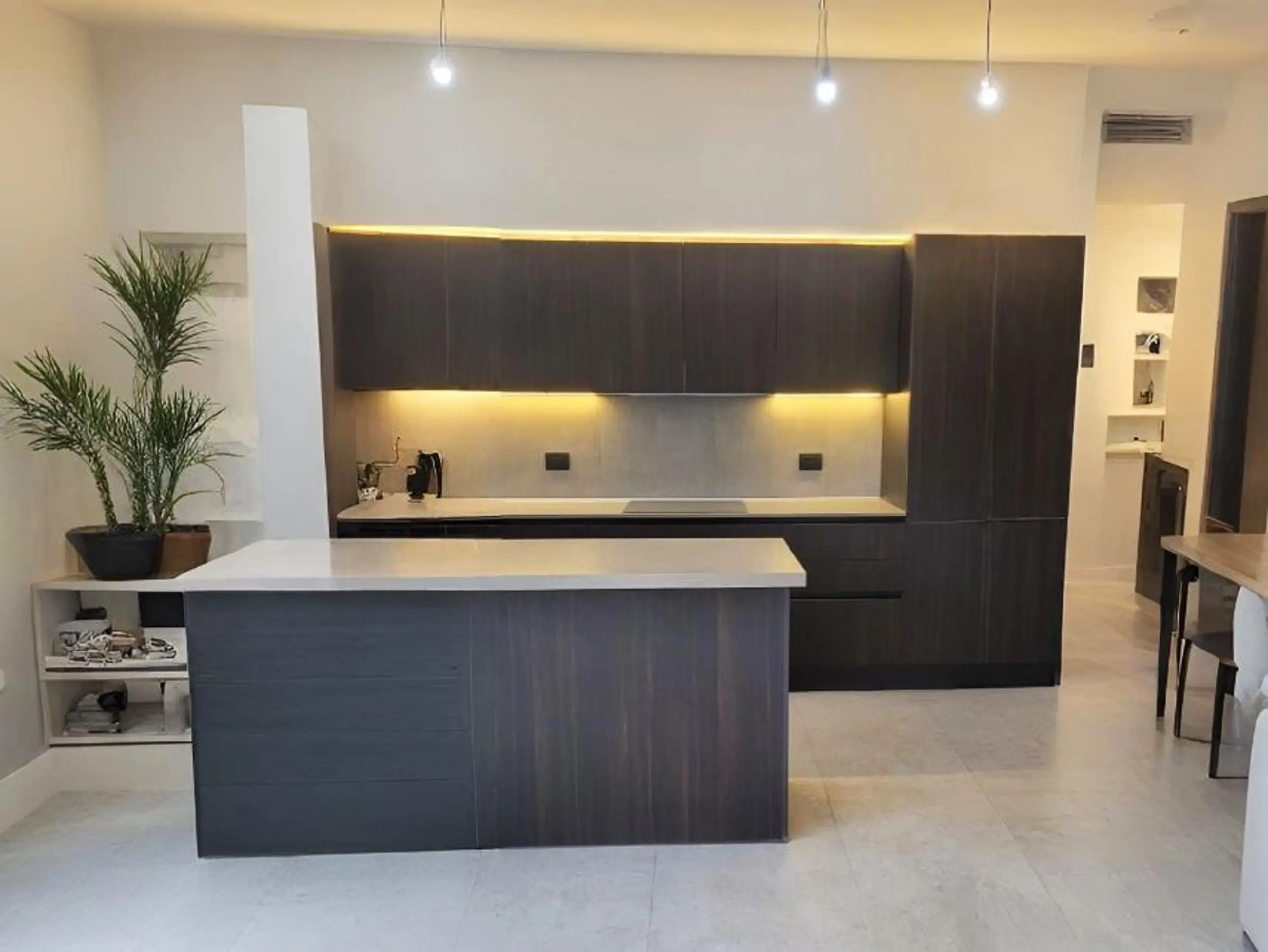 Cocina moderna con melamina oscura, cubierta clara tipo cuarzo, iluminación LED y diseño funcional, proyecto exclusivo de Style Muebles en Santiago de Chile